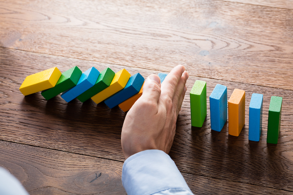 Person,Hand,Stopping,Falling,Dominoes,From,Continuous,Toppled,On,Wooden